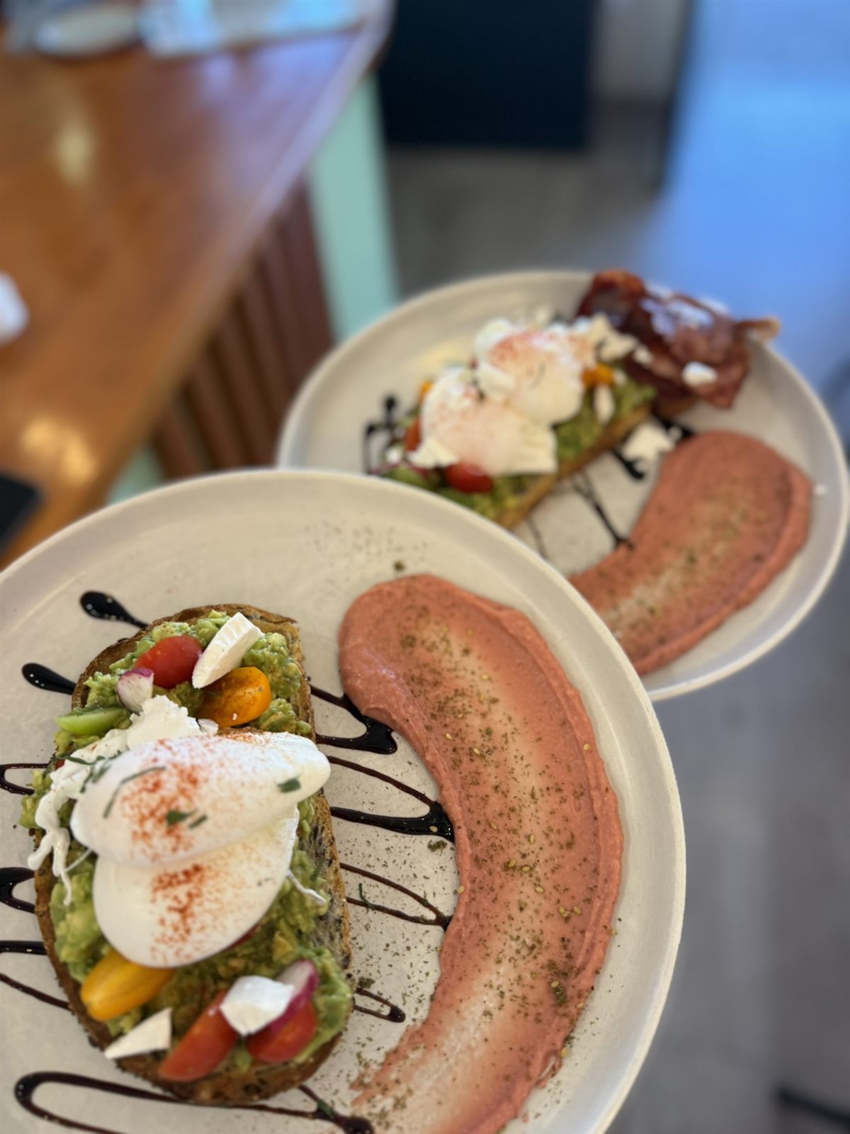 Smashed avo on sourdough topped with a poached egg, feta and beetroot hummus