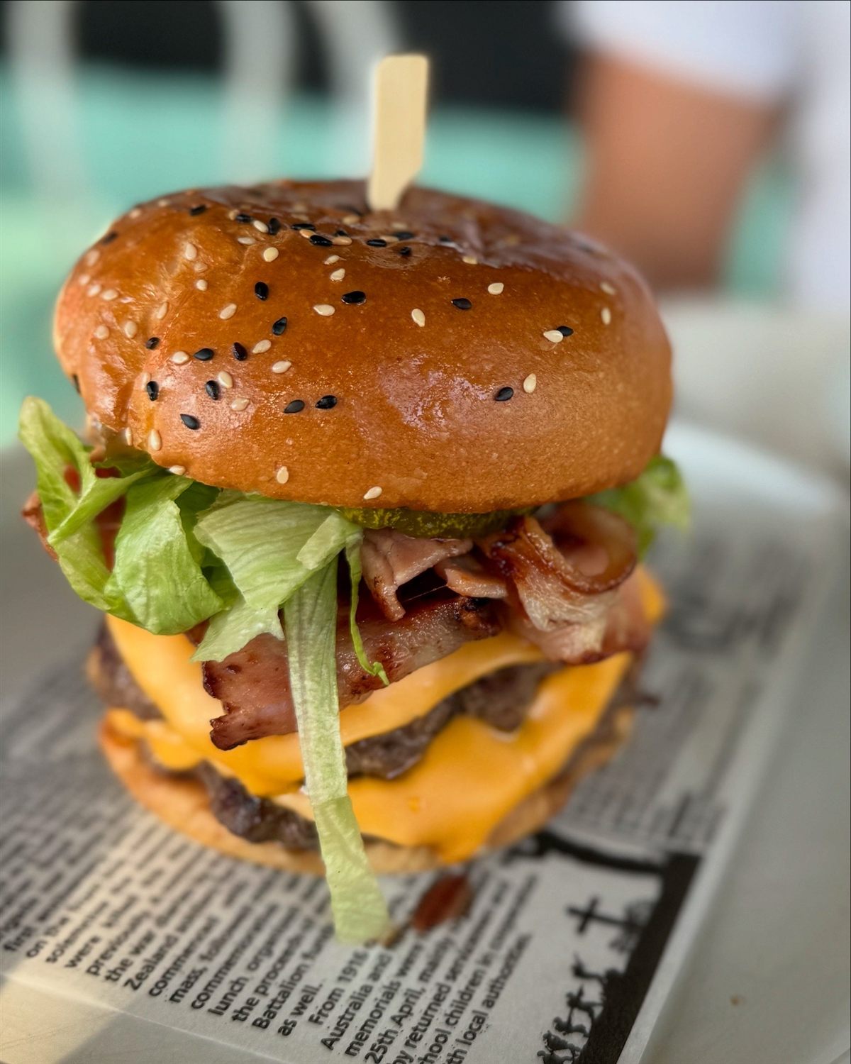 A stacked double cheeseburger with bacon on a sesame brioche bun